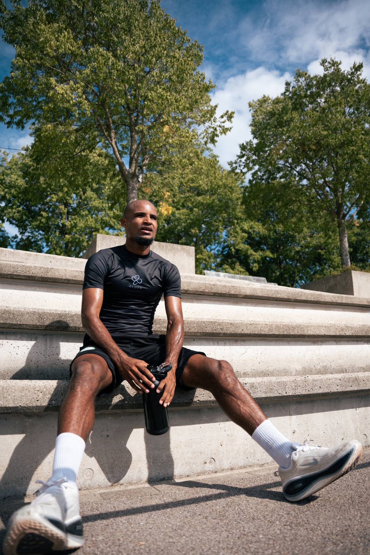 Athlète assis sur des gradins après l'effort, maillot de compression CLOVR noir